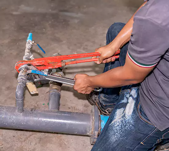 Licensed plumber repairing a copper pipe leak in a Washington basement